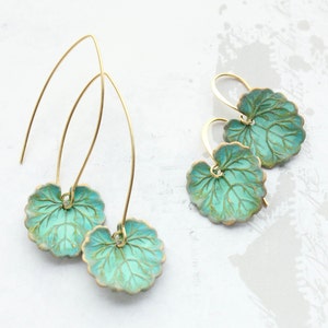 Peut inclure: Une paire de boucles d'oreilles pendantes dorées avec des breloques en forme de feuille vert turquoise. Les feuilles ont un design texturé et veiné.