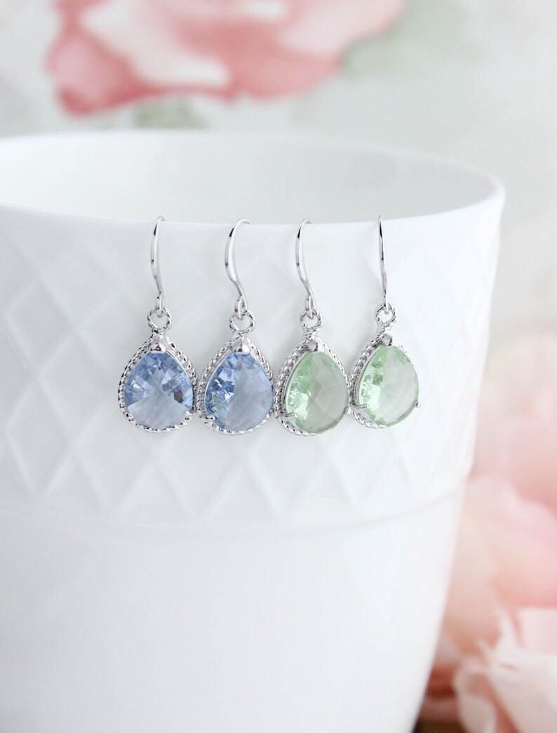 Puede incluir: Cuatro pares de pendientes en forma de l&aacute;grima con ganchos plateados. Los pendientes presentan piedras facetadas de color azul claro y verde.