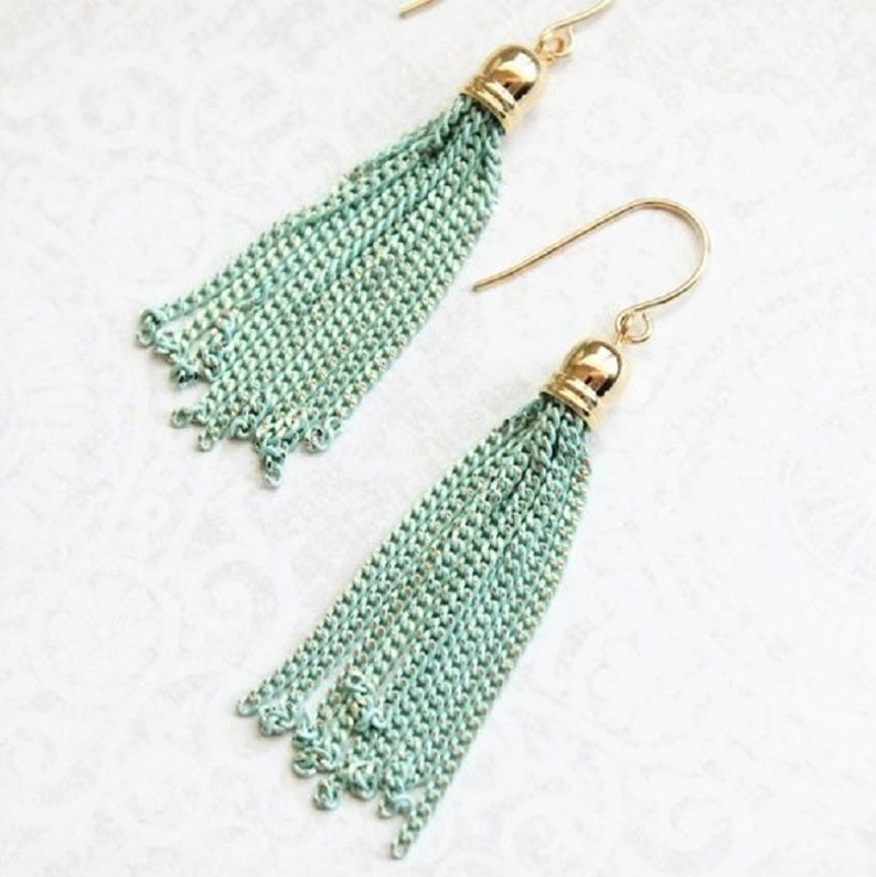 May include: A pair of mint green tassel earrings with gold hooks and tops. The tassels are made of chain links.