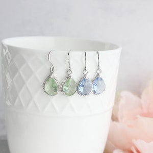 Puede incluir: Tres pares de pendientes colgantes en forma de l&aacute;grima con engastes plateados. Los pendientes presentan piedras de color verde claro, azul claro y azul oscuro.
