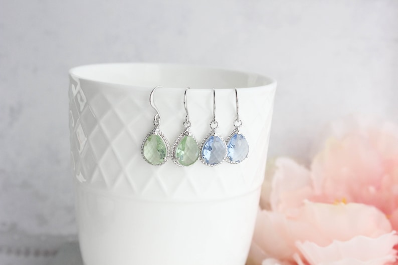 Puede incluir: Tres pares de pendientes colgantes en forma de l&aacute;grima con engastes plateados. Los pendientes presentan piedras de color verde claro, azul claro y azul oscuro.