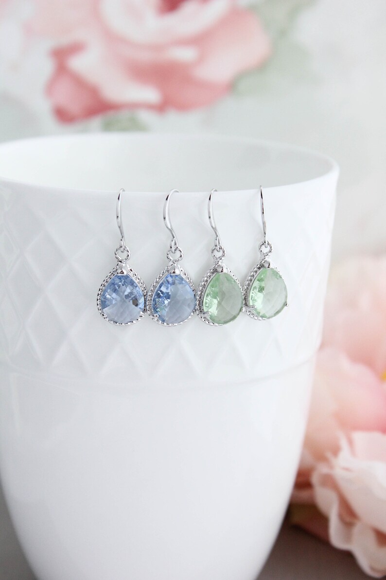 Puede incluir: Tres pares de pendientes colgantes en forma de l&aacute;grima con ganchos plateados. Los pendientes presentan piedras de cristal facetadas en azul claro y verde claro.