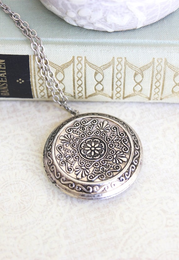 Lot - A VICTORIAN STYLE LARGE SILVER LOCKET PENDANT; oval locket engraved  front and back with beaded edge opening to twin compartment, siz...