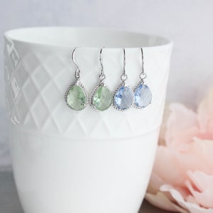 Puede incluir: Tres pares de pendientes colgantes en forma de l&aacute;grima con engastes plateados. Los pendientes presentan piedras preciosas de color verde claro, azul claro y azul oscuro.