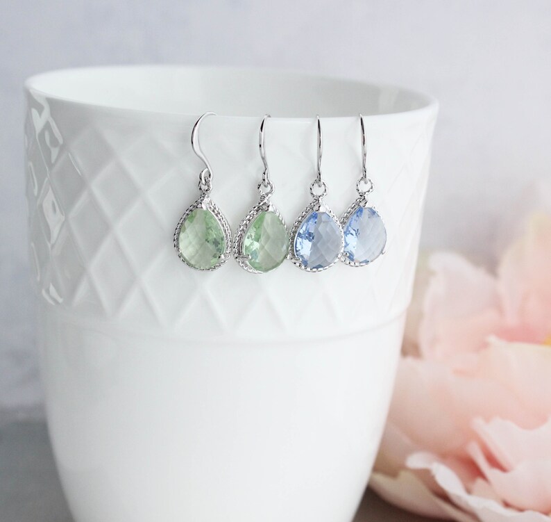 Puede incluir: Tres pares de pendientes colgantes en forma de l&aacute;grima con engastes plateados. Los pendientes presentan piedras preciosas de color verde claro, azul claro y azul oscuro.