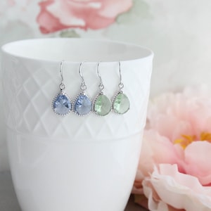 Puede incluir: Tres pares de pendientes colgantes en forma de l&aacute;grima con ganchos plateados. Los pendientes presentan una piedra preciosa azul claro, azul oscuro y verde claro.