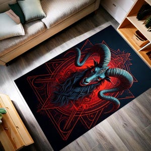 May include: A rectangular black area rug featuring a detailed illustration of a ram's head with large, curved horns. The ram is depicted in shades of blue and teal, set against a red geometric design. The rug is placed on a wooden floor.