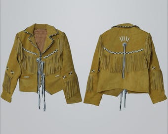 May include: Mustard-colored suede jacket with fringe detailing. The jacket features white and black accents along the collar, cuffs, and front closure. The back of the jacket has a decorative design with fringe and white stitching. A stylish outerwear piece.