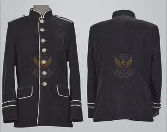 May include: Black velvet jacket with white trim and decorative buttons. Features a mandarin collar and front pockets. The jacket has a logo on the front and back. The jacket is a formal wear garment.