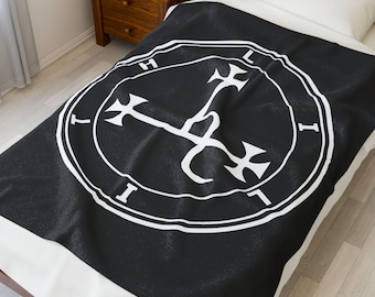 May include: Black blanket with a white circular design featuring a stylized symbol and the letters "I", "H", and "L". The blanket is draped over a bed with a white pillow and a wooden nightstand.