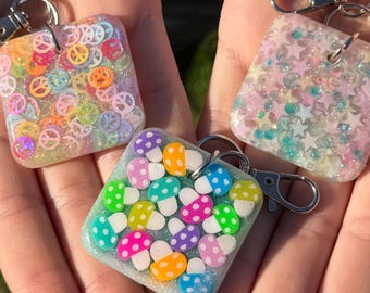 Llavero cuadrado de resina con purpurina / Lindo colgante para bolso hecho a mano / Llavero de resina colorido / Seta arcoíris, estrella cósmica, paz y amor