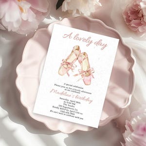 May include: A pink invitation card with the text "A lovely day" and "Madeline's birthday". The card features watercolor illustrations of ballet shoes with pink ribbons. The card is on a pink plate, surrounded by pink flowers.