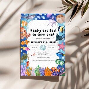 May include: A blue invitation card with watercolor illustrations of sea creatures, including fish, a shark, and a jellyfish. The text reads "Reel-y excited to turn one!" and announces Anthony's 1st birthday party.