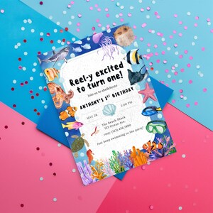 May include: A colorful invitation with an underwater theme. The text reads "Reel-y excited to turn one!" with details for Anthony's 1st birthday. The design includes various sea creatures like fish, a shark, and a starfish, with a blue and pink background.