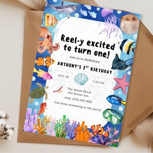 May include: An invitation for a first birthday party with an ocean theme. The invitation features watercolor illustrations of various sea creatures, including fish, a shark, and a starfish, with the text "Reel-y excited to turn one!"