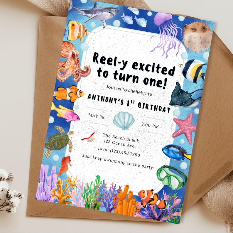 May include: An invitation for a first birthday party with an ocean theme. The invitation features watercolor illustrations of various sea creatures, including fish, a shark, and a starfish, with the text "Reel-y excited to turn one!"