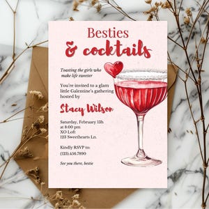 以下が含まれることがあります： 「Besties & cocktails」の赤い筆記体で書かれたピンク色の招待状。赤い飲み物とハートが入ったカクテルグラスの水彩イラストが特徴です。招待状は、Stacy Wilsonが主催するGalentine'sの集まり用です。