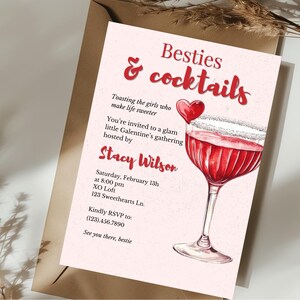 以下が含まれることがあります： 「Besties & cocktails」の赤い筆記体で書かれたピンク色のバレンタインデーの招待状。招待状には、カクテルの水彩イラストとハートが含まれています。テキストは、Stacy Wilsonが主催する集まりにゲストを招待しています。