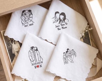 Pode incluir: Quatro lenços brancos com bordas festonadas apresentando ilustrações bordadas em preto de casais e famílias. Os designs incluem textos como EST. 2022, Love You to the Moon e 2025.08.14 com um pequeno coração vermelho entre as letras D e K.