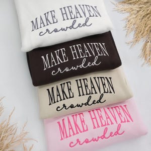 May include: Four sweatshirts in a stack, in cream, brown, beige, and pink. Each has the embroidered phrase "MAKE HEAVEN crowded" in a contrasting colour.