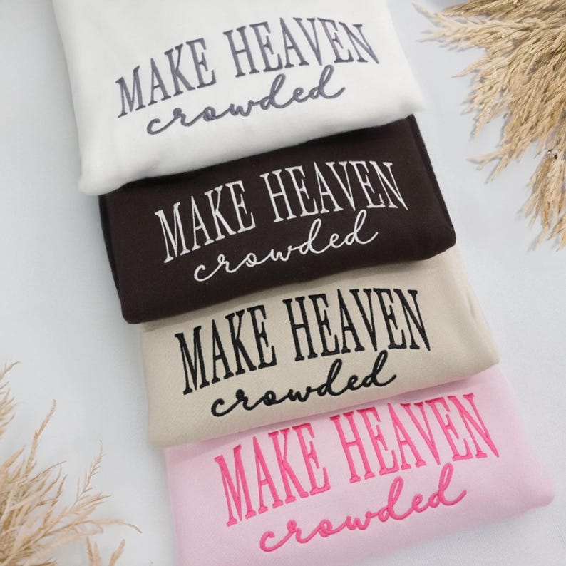 May include: Four sweatshirts in a stack, in cream, brown, beige, and pink. Each has the embroidered phrase "MAKE HEAVEN crowded" in a contrasting colour.