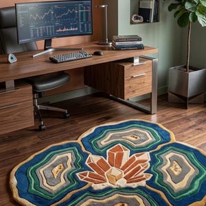 May include: A colorful, geode-shaped rug with a central crystal design. The rug features shades of blue, green, gold, and orange, creating a layered effect. It's placed on a wooden floor, complementing the office setting.