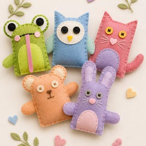 May include: A collection of handmade felt animal toys, including a green frog, blue owl, pink cat, orange bear, and purple rabbit. Each toy has button eyes and is surrounded by felt hearts and leaves.