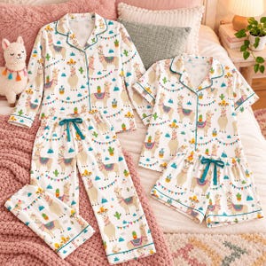 May include: A set of white pajamas featuring a repeating pattern of llamas, cacti, and colorful bunting. The set includes a long-sleeve button-down top, a short-sleeve button-down top, long pants with a drawstring waist, and shorts.