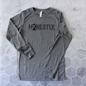 Op de afbeelding: Grijs longsleeve t-shirt met een zwart-witte afbeelding van Abraham Lincoln's gezicht en het woord "HONESTLY".