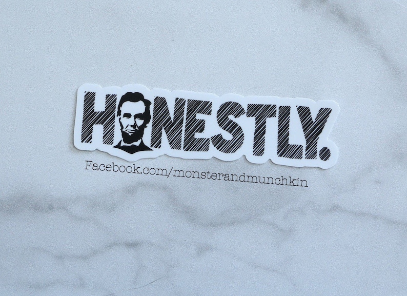 May include: Black and white sticker with the word "HONESTLY" in a stylized font. The word is outlined in black and has a textured, hatched pattern. A black and white image of Abraham Lincoln is incorporated into the "H" of the word. The sticker also includes the text "Facebook.com/monsterandmunchkin".