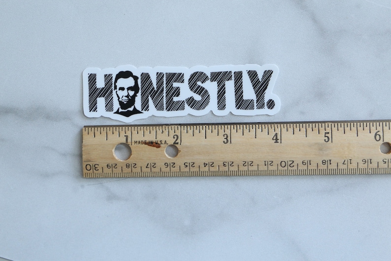 May include: A white sticker with black text that reads "HONESTLY."  The text is in a stylized font with a black and white image of Abraham Lincoln's face in the "H".