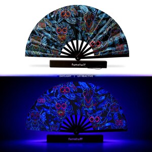 May include: A folding hand fan with a black frame and a fabric canopy featuring a repeating pattern of owls in neon colors against a dark background. The base of the fan is labeled with the text funxtuff. The design is shown in daylight and under UV light.