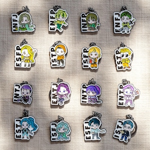 May include: A collection of sixteen enamel keychains, each featuring a cartoon character and a four-letter personality type acronym including INFJ, ENFP, INFP, ENFJ, ESFP, ISTP, ISFP, ESTP, INTJ, ENTJ, INTP, ENTP, ESTJ, ISFJ, ESFJ, and ISTJ.