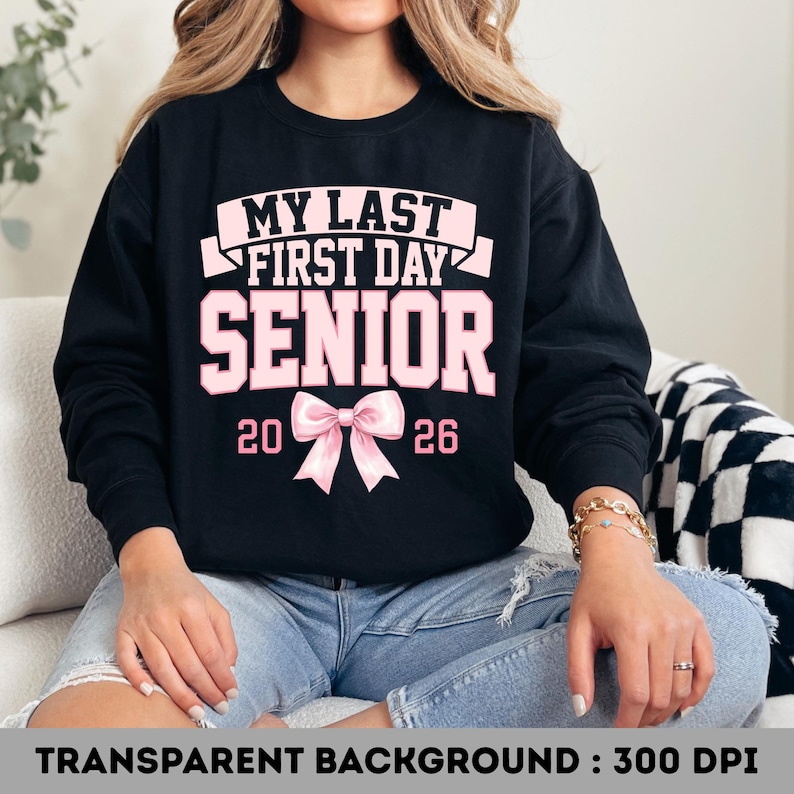 May include: Black sweatshirt with the text "MY LAST FIRST DAY SENIOR 2026" in pink. A pink bow is centered below the text. The sweatshirt is a senior year graduation design.
