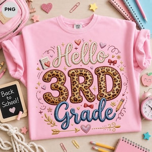 May include: A light pink crewneck sweatshirt featuring embroidered text that reads Hello 3RD Grade. The word Hello is in white, 3RD is in a brown leopard print, and Grade is in blue. The design includes small hearts, stars, bows, and pencils.