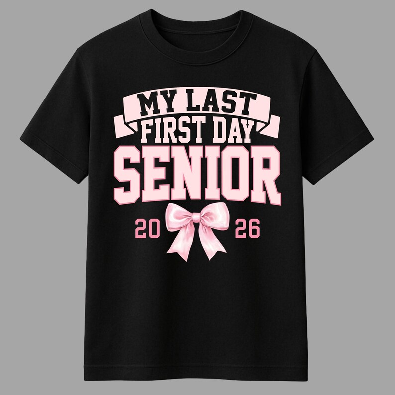 May include: Black t-shirt with the text "MY LAST FIRST DAY SENIOR 2026" in pink and white. A pink bow graphic is centered below the word "SENIOR". The shirt is a crew neck style.