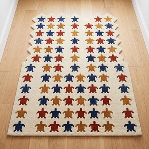Puede incluir: Una alfombra rectangular con fondo crema y un patrón de formas de tortugas coloridas. Las tortugas son en tonos azules, rojos y dorados. La alfombra tiene un borde único y festoneado.