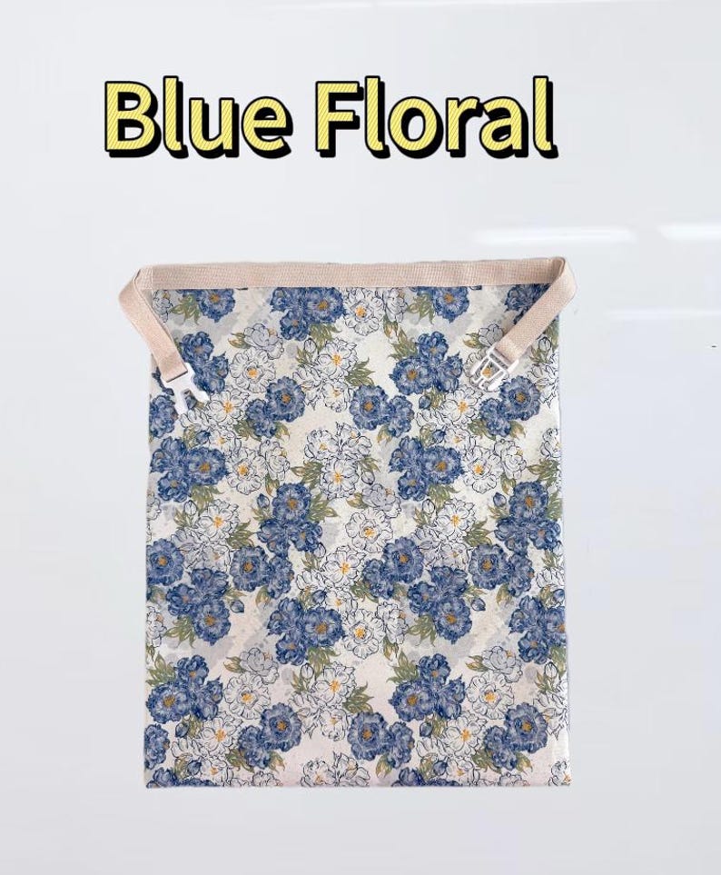 Peut inclure: Un sac en tissu rectangulaire avec un motif floral bleu sur fond blanc. Le sac comprend une sangle beige avec une boucle &agrave; d&eacute;gagement lat&eacute;ral en plastique blanc sur le dessus. Le texte "Blue Floral" est imprim&eacute; en jaune au-dessus du sac.