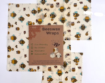 May include: Beeswax wraps featuring a cream background with a pattern of yellow and black bees and honey pots. The wraps are eco-friendly, reusable, washable, and sustainable. A brown card in the center reads "Beeswax Wraps".