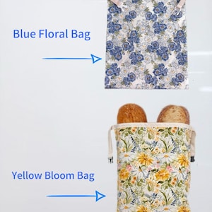 Op de afbeelding: Twee bloemenpatroon tassen worden getoond. De bovenste tas is wit met blauwe bloempatronen. De onderste tas, gevuld met brood, heeft een geel bloemenpatroon. De tekst luidt "Blue Floral Bag" en "Yellow Bloom Bag".