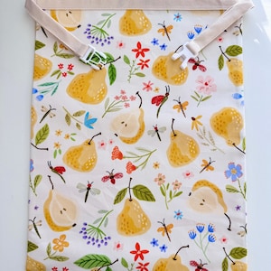 Op de afbeelding: Witte stoffen tas met een perenpatroon, met gele peren, kleurrijke bloemen en insecten. De tas heeft een beige band met een witte plastic gesp. De tekst "Pear pattern" staat bovenaan.