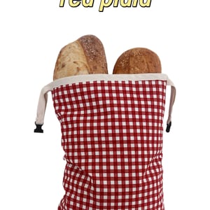 Peut inclure: Un sac &agrave; pain &agrave; motif vichy rouge et blanc avec une bordure sup&eacute;rieure cr&egrave;me et des boucles lat&eacute;rales en plastique noir. Deux miches de pain croustillantes sont visibles &agrave; l'int&eacute;rieur. Le texte "red plaid" est &eacute;crit en jaune au-dessus.