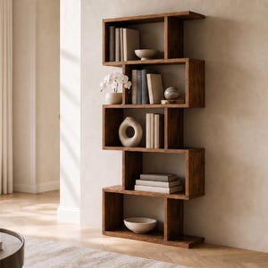 May include: A modern, zig-zag design bookshelf made of dark wood. The shelves are filled with books, decorative bowls, vases, and a small sculpture. The bookshelf is placed against a neutral-colored wall in a well-lit room.