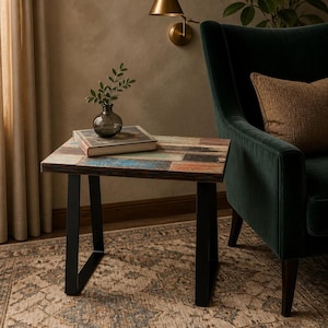 May include: A rectangular side table featuring a tabletop constructed from reclaimed wood planks with weathered blue, orange, and brown tones. The table is supported by two black metal U-shaped legs and holds a glass vase with a small green plant.