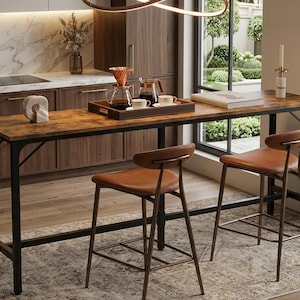 May include: A rustic-style bar table with a dark metal frame and a distressed wood-look top. Two brown leather bar stools are positioned in front of the table. The kitchen setting includes a marble backsplash and a patterned rug.