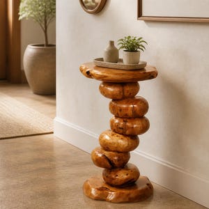 May include: A side table constructed from a stack of polished, rounded wooden segments that create a spiraling, organic column. The table features a flat, circular top surface and a matching base, showcasing a warm, natural wood grain finish.