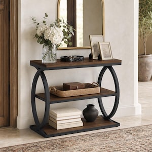 May include: A console table with a dark wood finish and a black metal frame featuring circular side supports. The table has three tiers, with a glass vase of white flowers, a marble tray, and two picture frames on the top shelf, a woven tray with a box on the middle shelf, and a stack of books and a black vase on the bottom shelf.