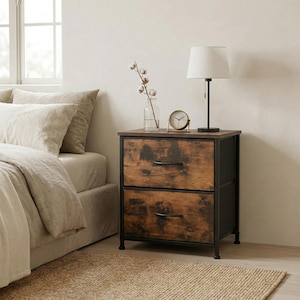 May include: A two-drawer nightstand with a rustic, distressed wood finish and black metal frame. The nightstand has a lamp, a small clock, and a vase with a cotton stem on top. The nightstand is next to a bed with beige bedding.