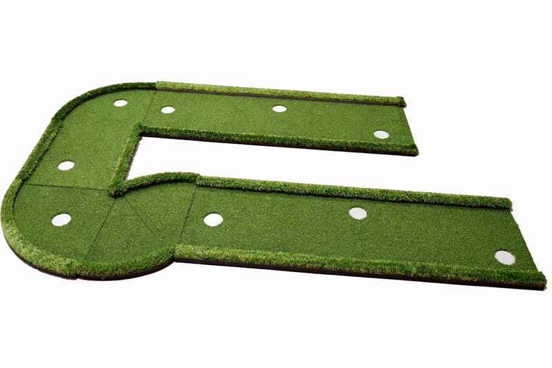 Puede incluir: Un green de golf artificial verde en forma de L con m&uacute;ltiples hoyos blancos. El green est&aacute; dise&ntilde;ado para uso en interiores o exteriores. Est&aacute; hecho de c&eacute;sped artificial y tiene una esquina curva.