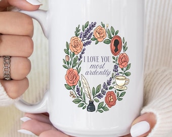 May include: White ceramic mug featuring a floral wreath design with the text "I love you most ardently." The wreath includes roses, lavender, and other botanical elements. A silhouette, teacup, and quill are also featured.